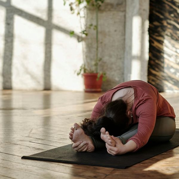Woman in a peaceful morning yoga pose in a sunlit room.